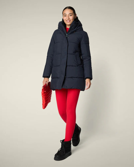 Black blue puffer on a woman with red pants against a plain background.