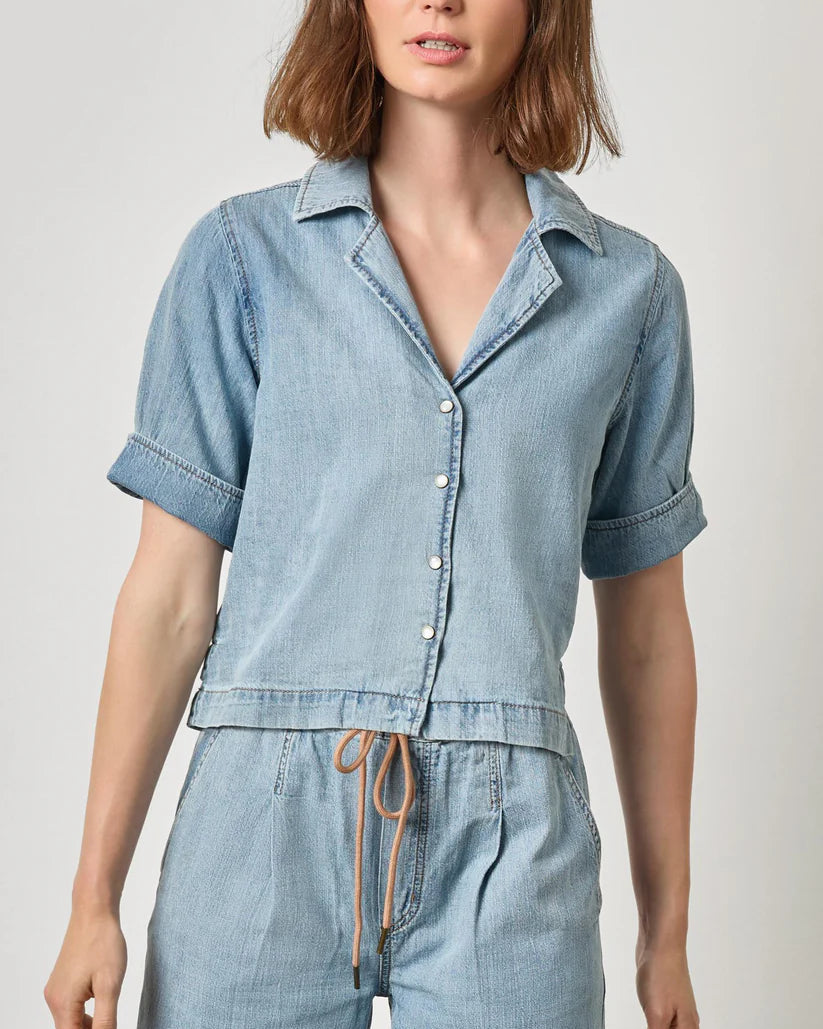 Woman wearing a light blue denim outfit on a plain background