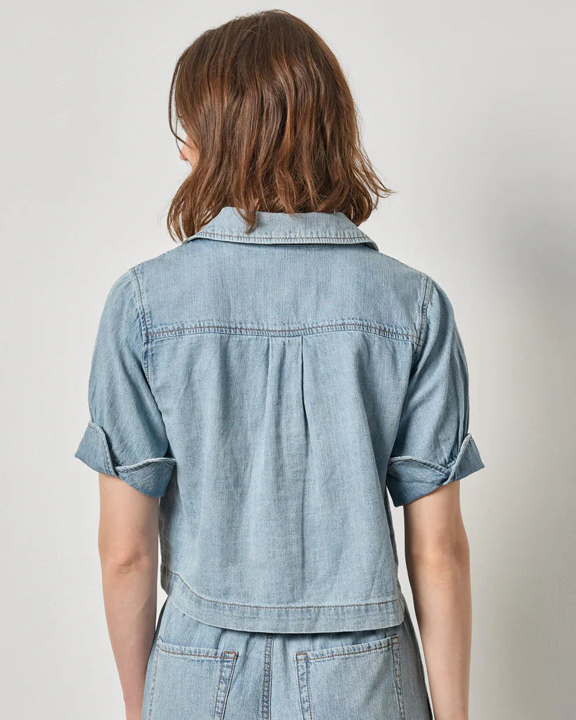 Person wearing a light blue denim outfit on a plain background