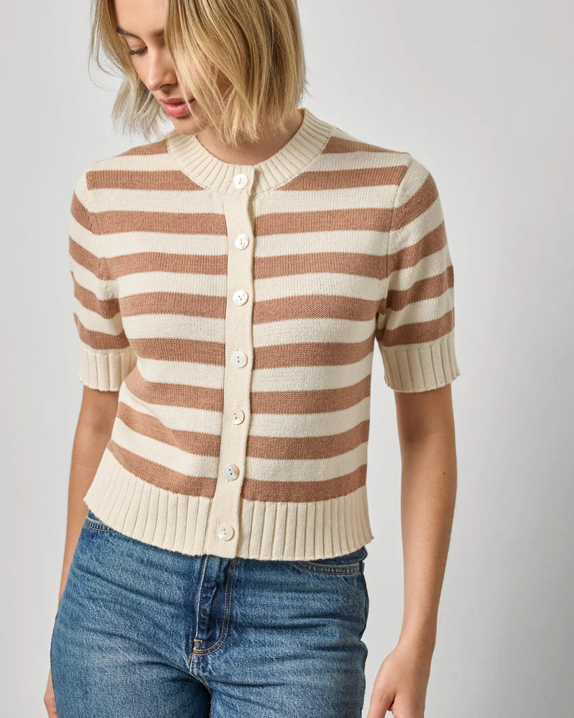 Woman wearing a striped sweater and jeans against a plain background