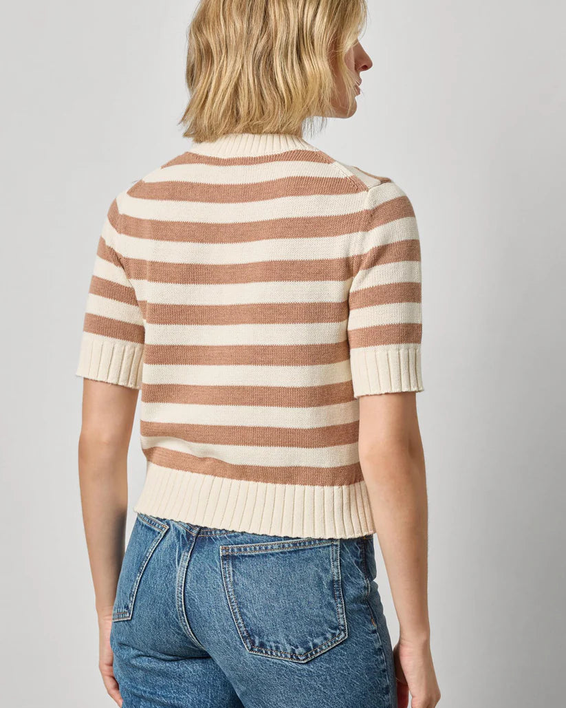 Person wearing a striped sweater and jeans against a plain background
