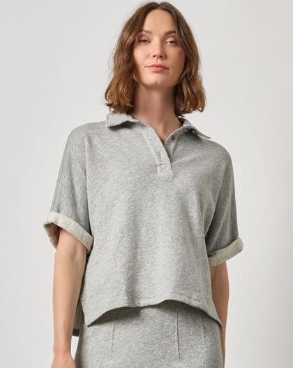 Woman wearing a gray short-sleeve shirt and skirt on a light gray background