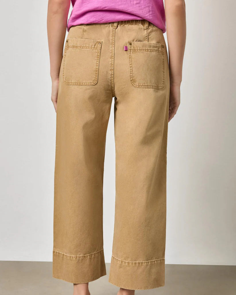 Person wearing beige wide-leg pants and a pink top on a plain background