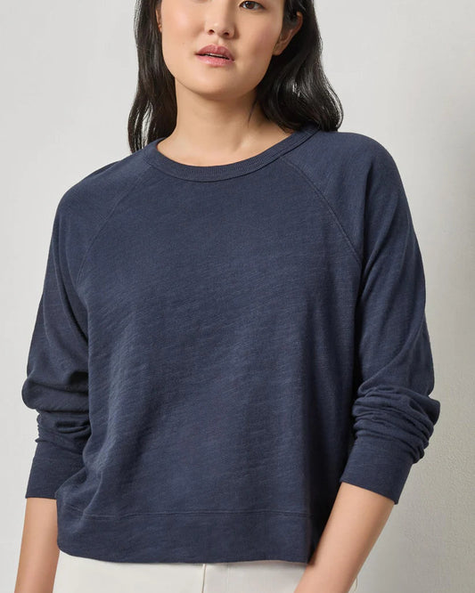 Woman wearing a navy blue sweater against a plain background