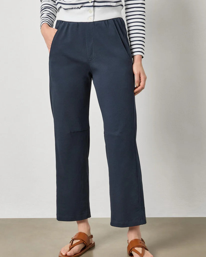 Person wearing navy pants and a striped shirt on a plain background