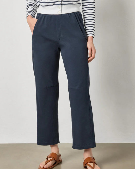 Person wearing navy pants and a striped shirt on a plain background