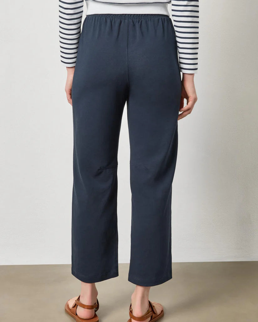 Person wearing navy wide-leg pants and a striped shirt against a plain background