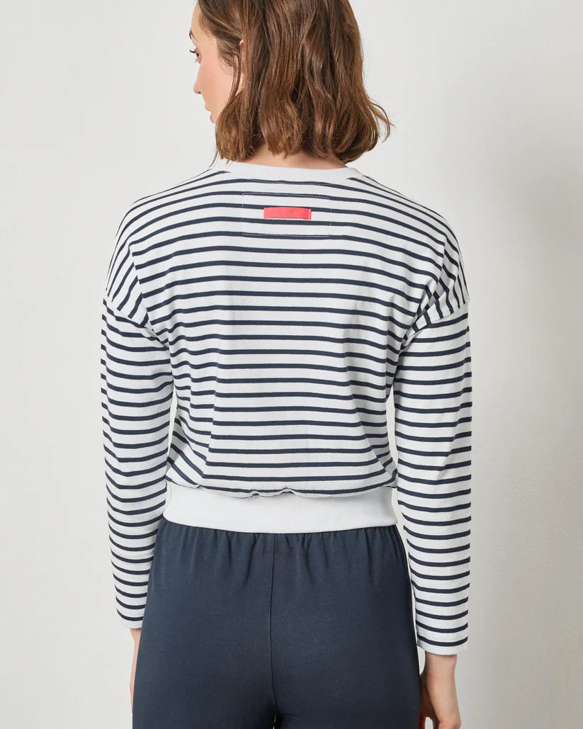 Person wearing a striped long-sleeve shirt with a visible brand logo on a plain background