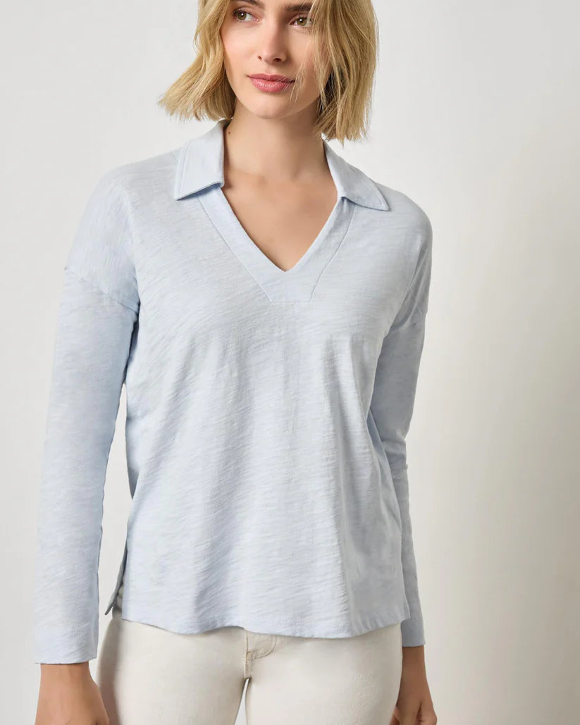 Woman wearing a light blue long-sleeve shirt against a plain background