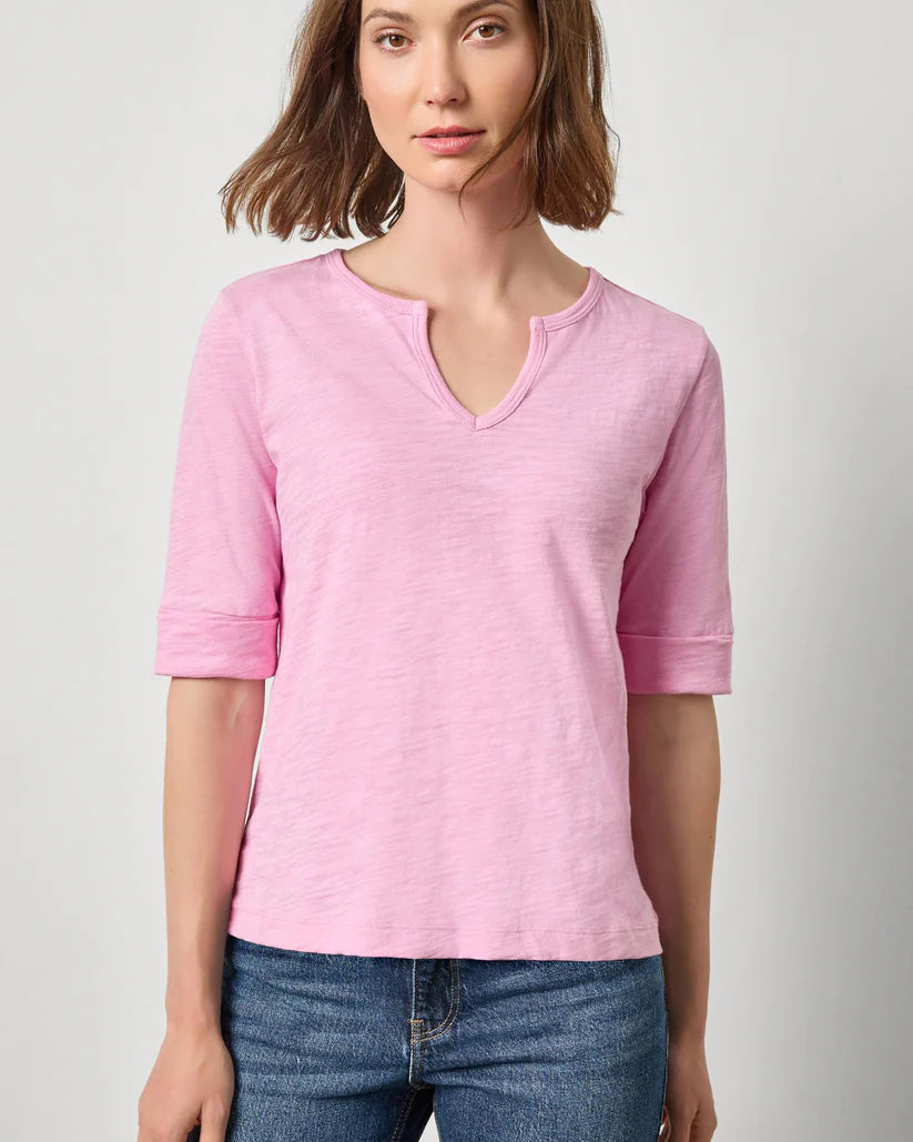 Woman wearing a pink shirt and blue jeans on a plain background