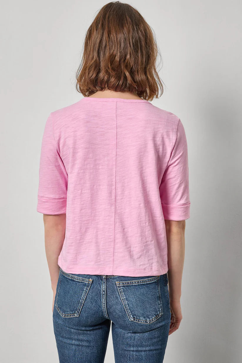 Person wearing a pink top and blue jeans against a plain background