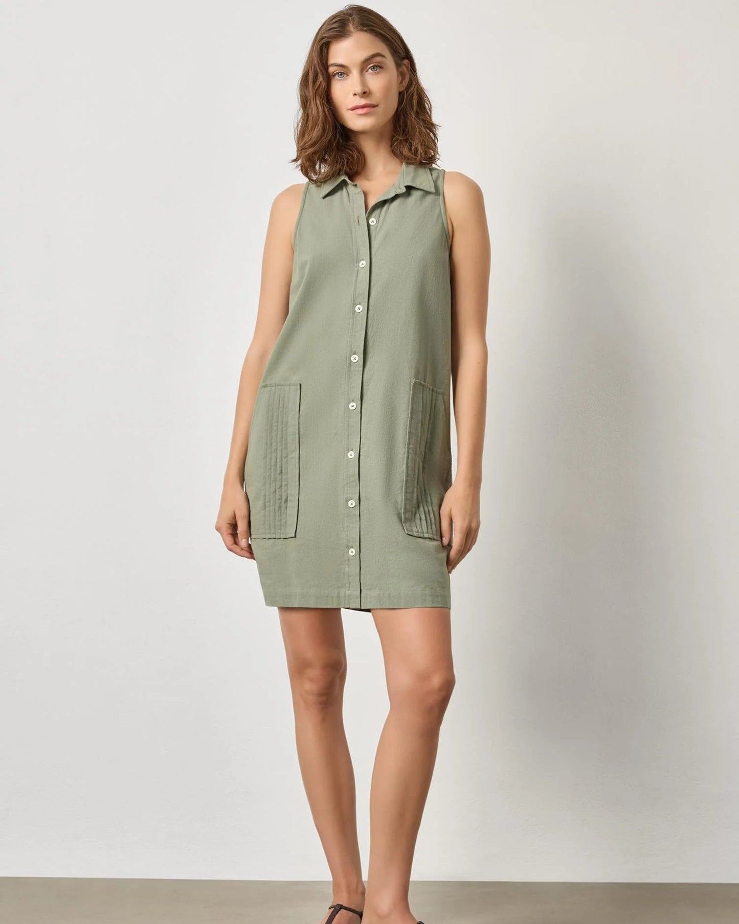 Woman wearing a green sleeveless dress against a white background