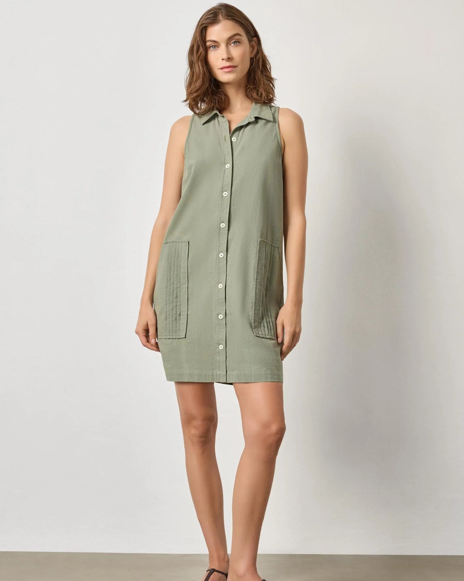 Woman wearing a green sleeveless dress against a white background