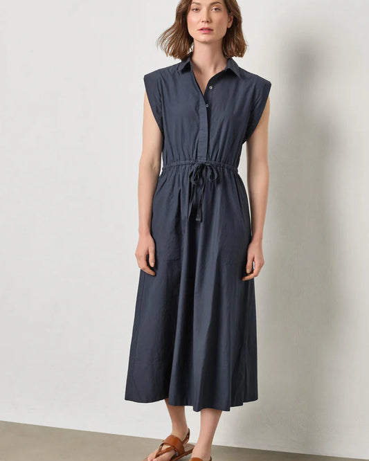 Woman wearing a navy dress against a plain background