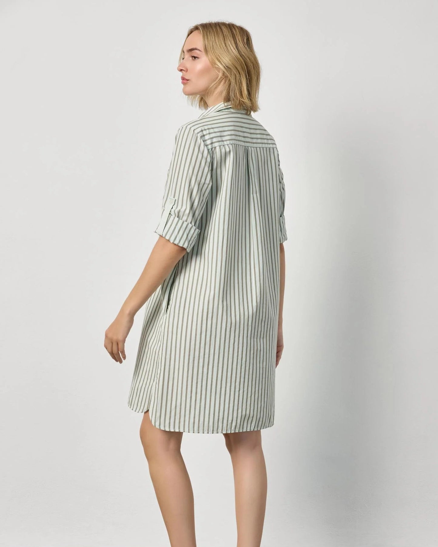 Woman wearing a green and white striped dress against a plain background