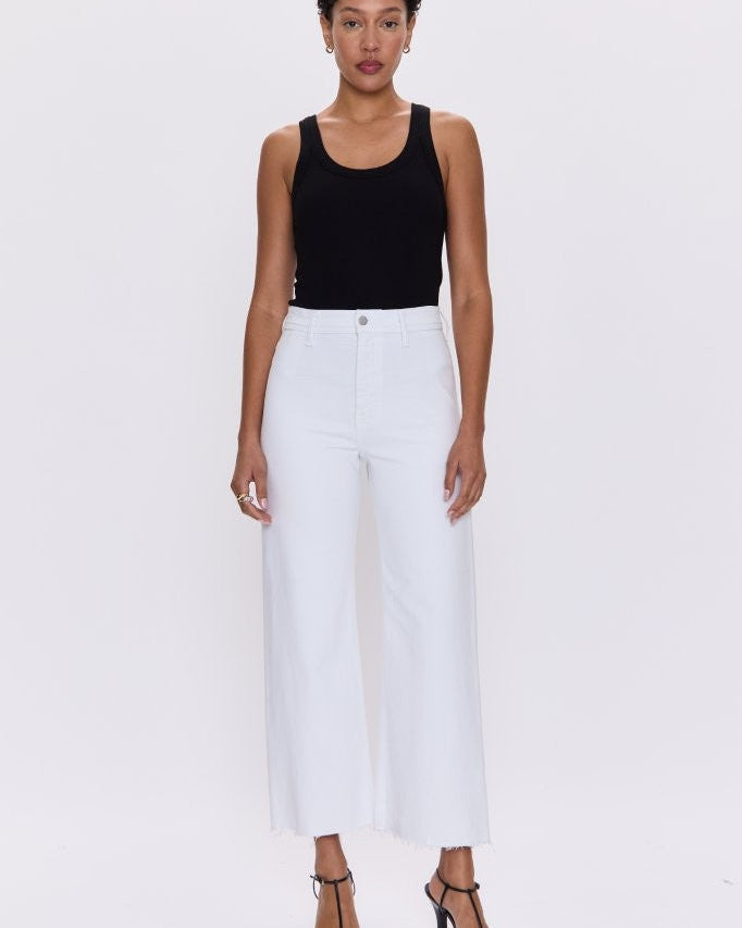 Woman wearing a black tank top and white pants on a white background