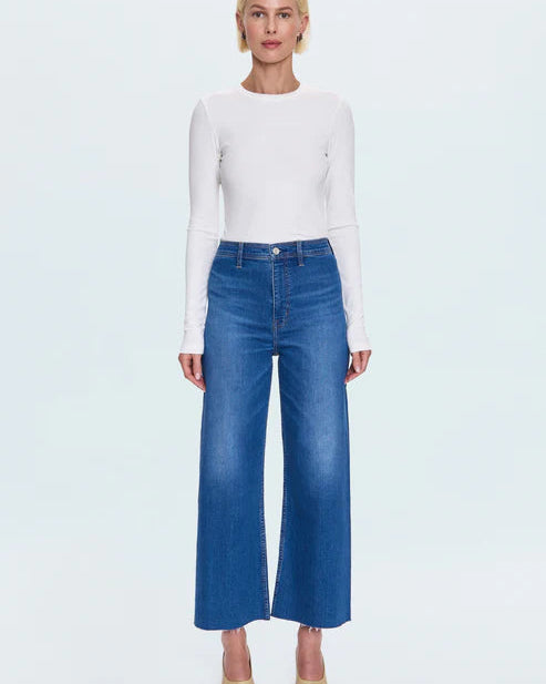 Person wearing a white top and blue jeans on a light gray background