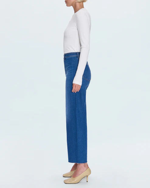 Woman wearing a white top and blue jeans on a light gray background