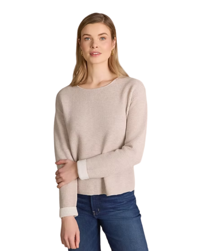 Woman wearing a beige sweater and blue jeans on a white background