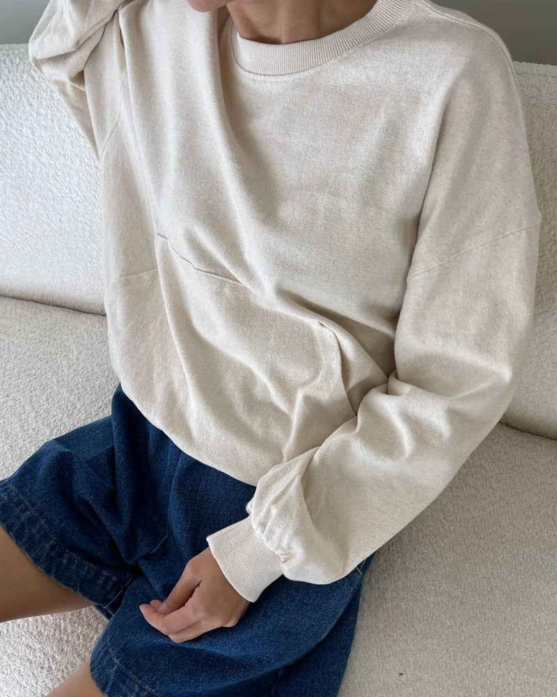 Model wearing the Le Bon Shoppe Poche top in natural with denim shorts sitting on an off white sofa.