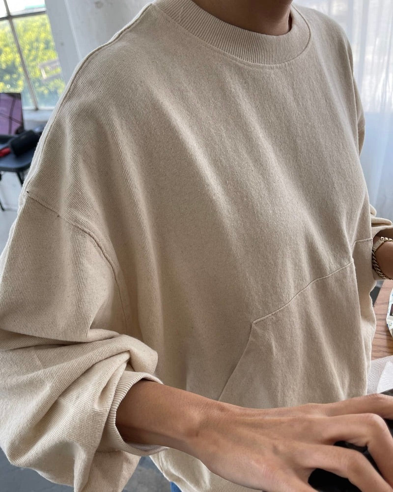 Side view of a model wearing the Le Bon Shoppe Poche top in natural standing at a desk.