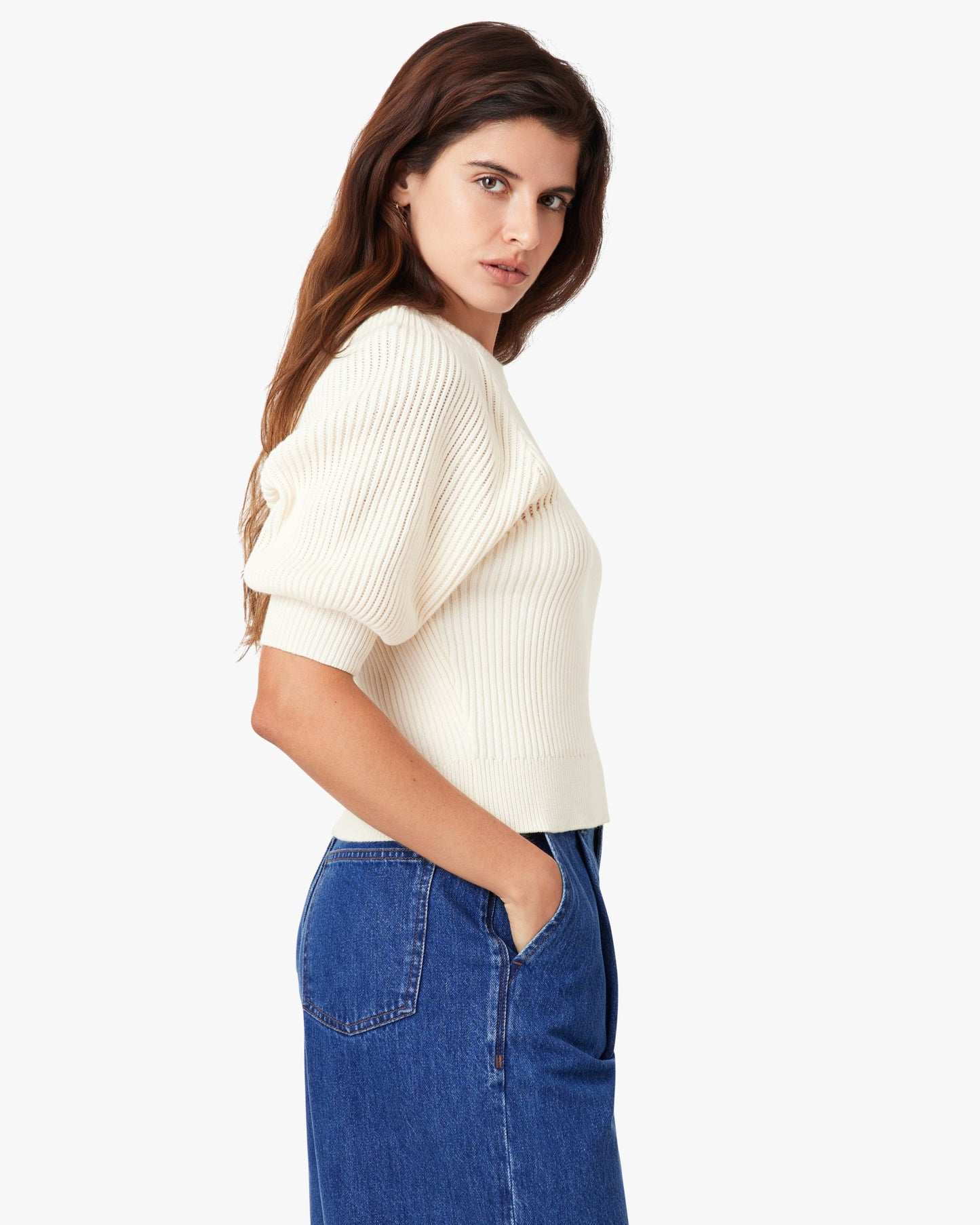 Woman wearing a white sweater and blue jeans on a white background