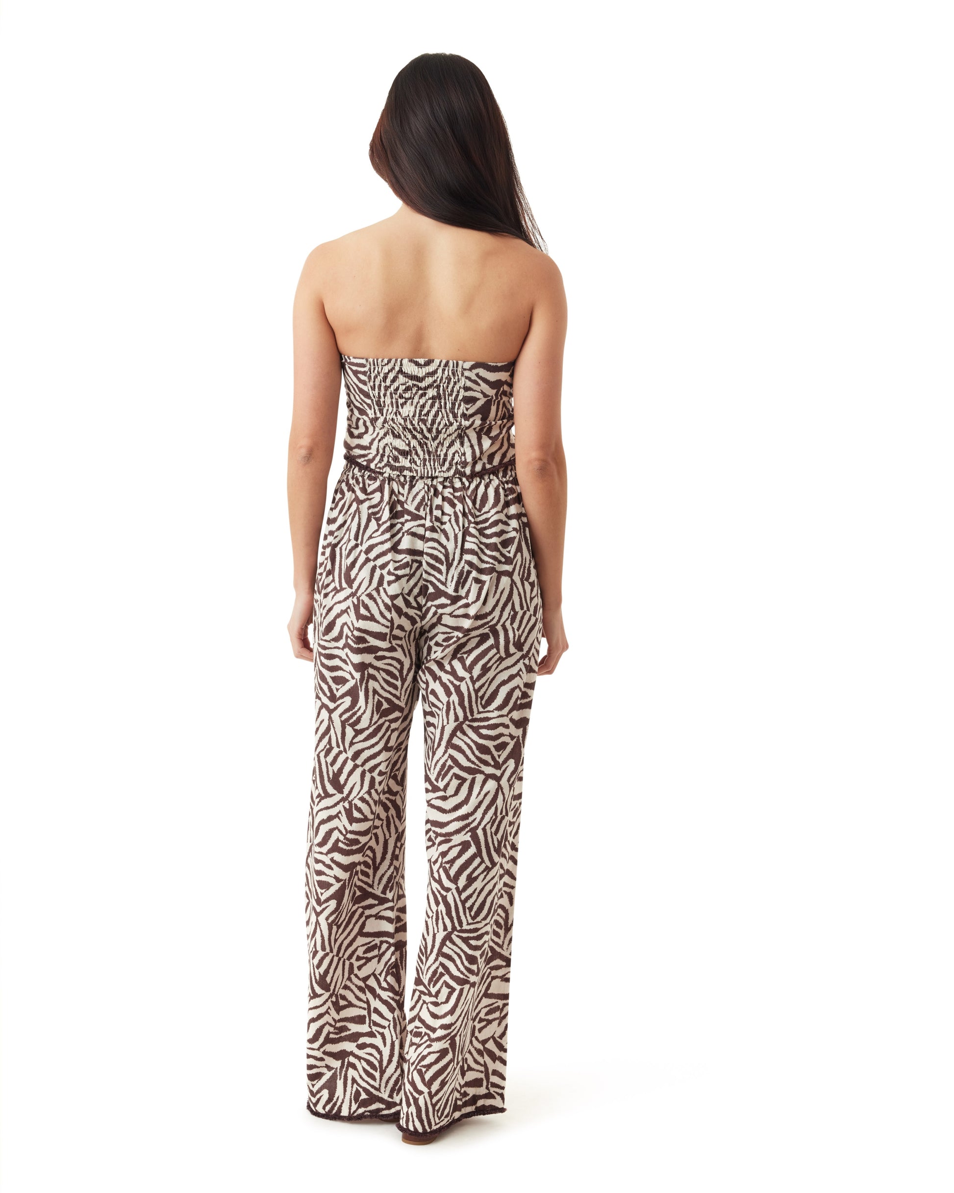 Woman wearing a strapless zebra print jumpsuit on a white background