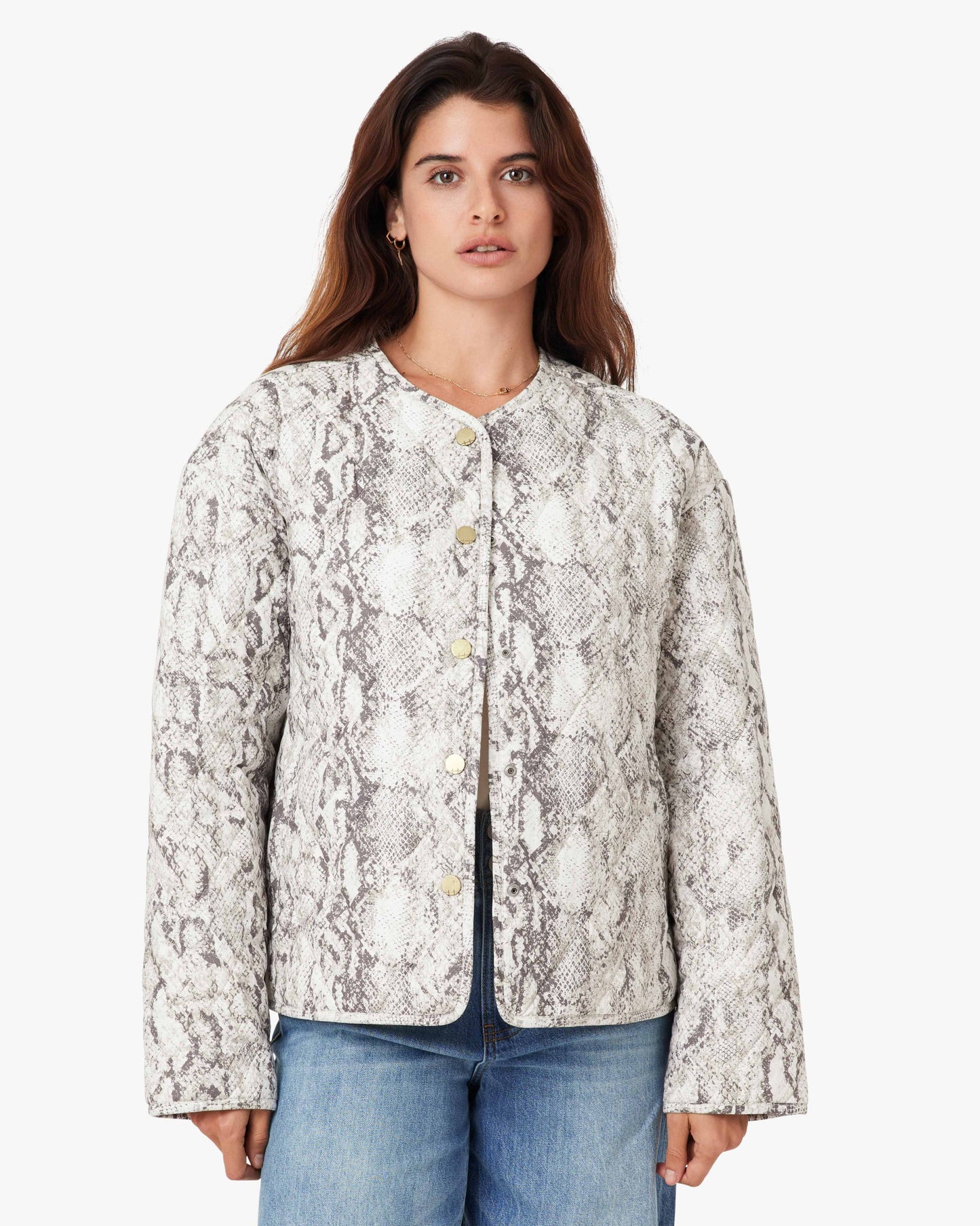 Woman wearing a patterned jacket and jeans on a white background