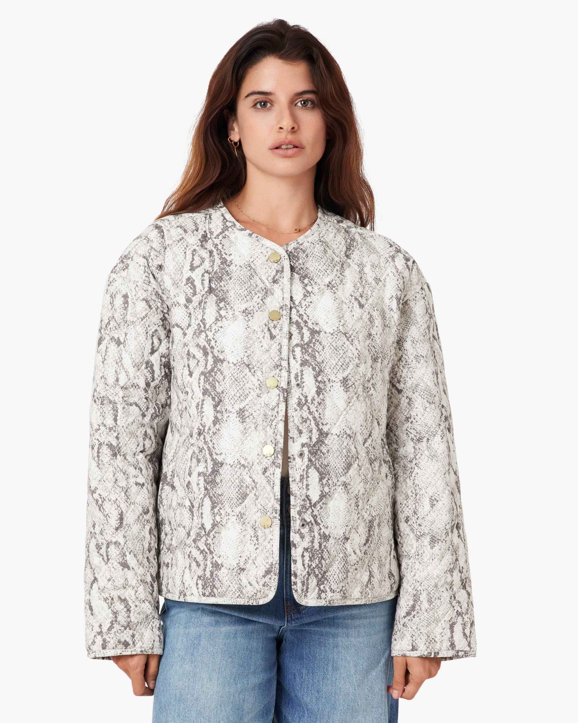 Woman wearing a patterned jacket and jeans on a white background