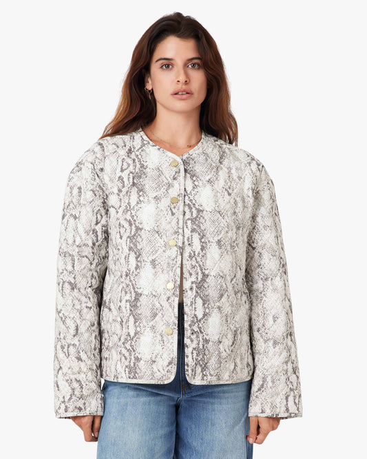 Woman wearing a patterned jacket and jeans on a white background