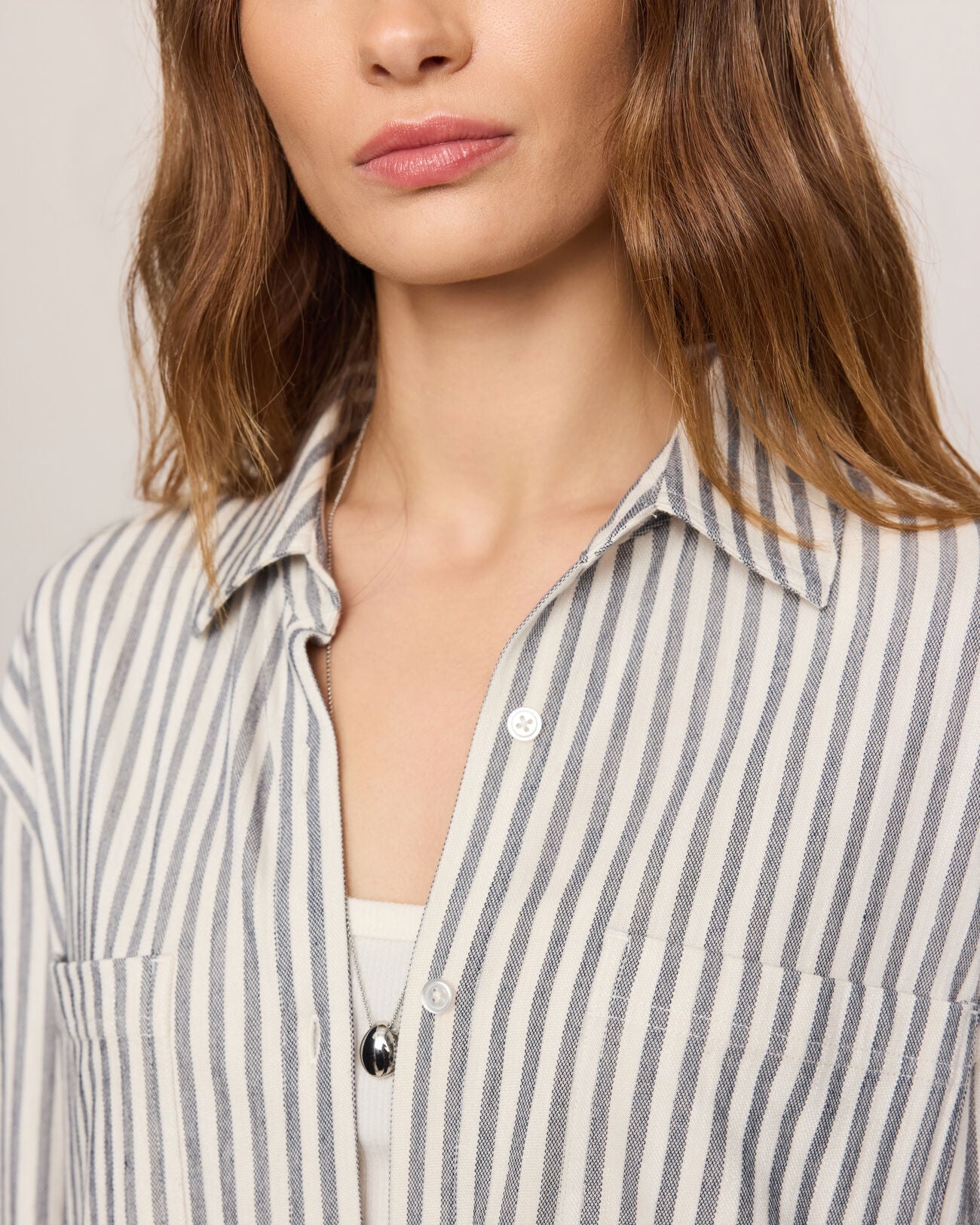 Close-up of a person wearing a striped shirt with a neutral background