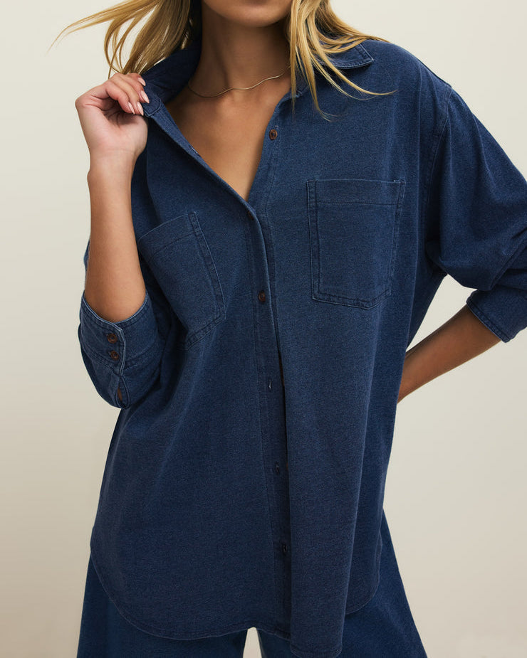 Woman wearing a blue denim shirt against a beige background