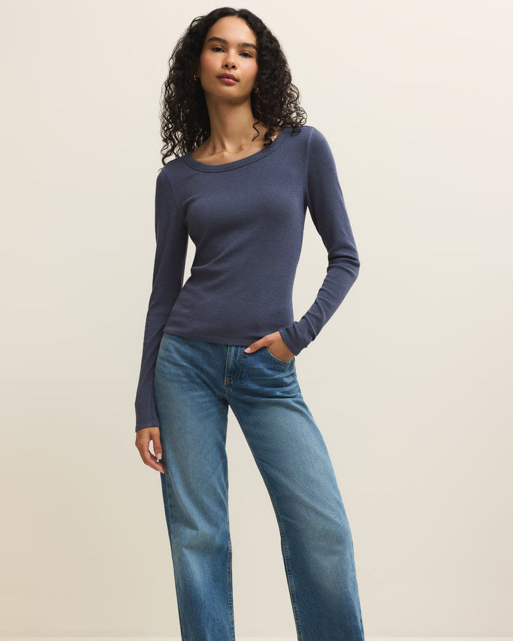 Woman wearing a blue long-sleeve top and jeans on a white background