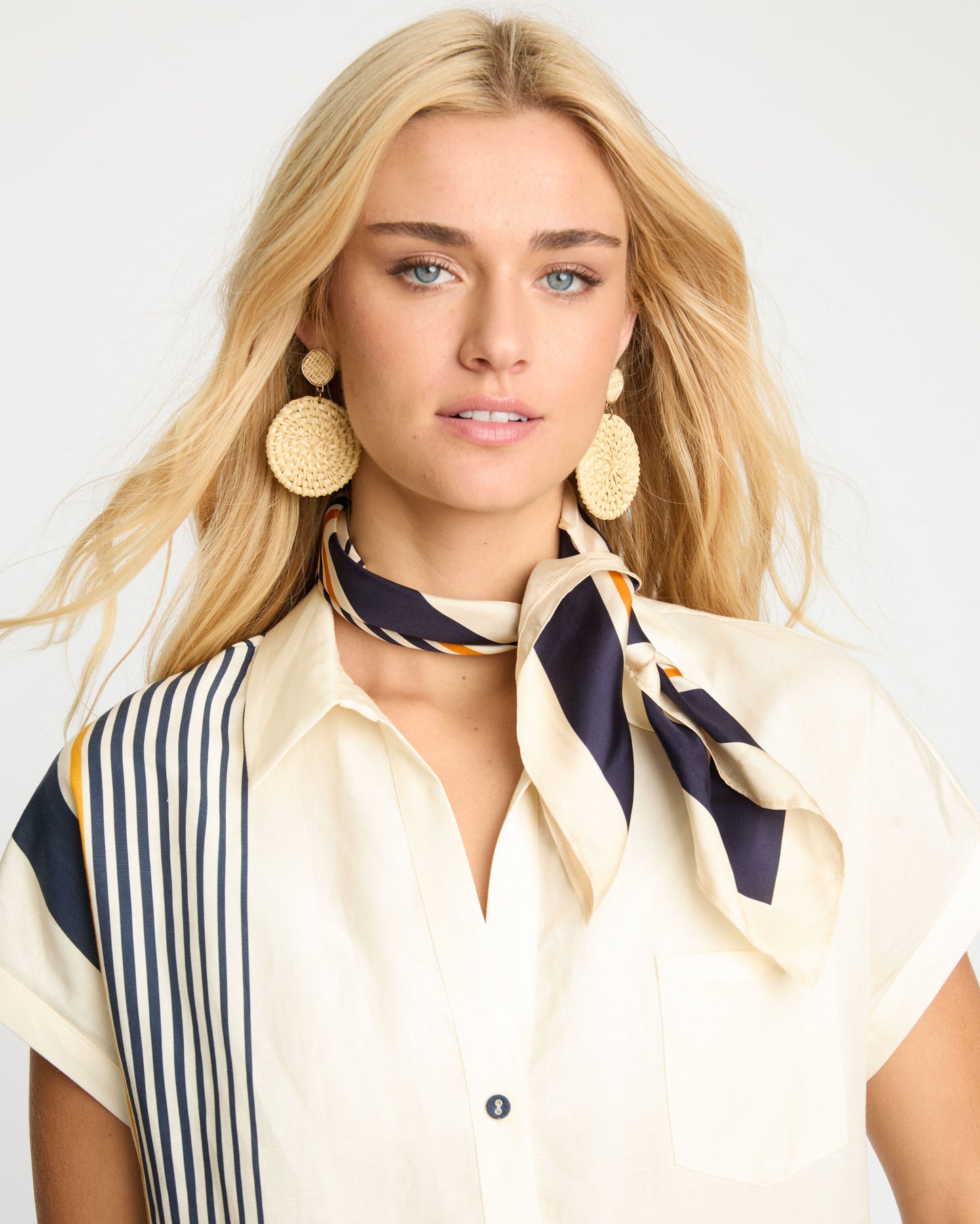Woman wearing a striped scarf and earrings against a white background