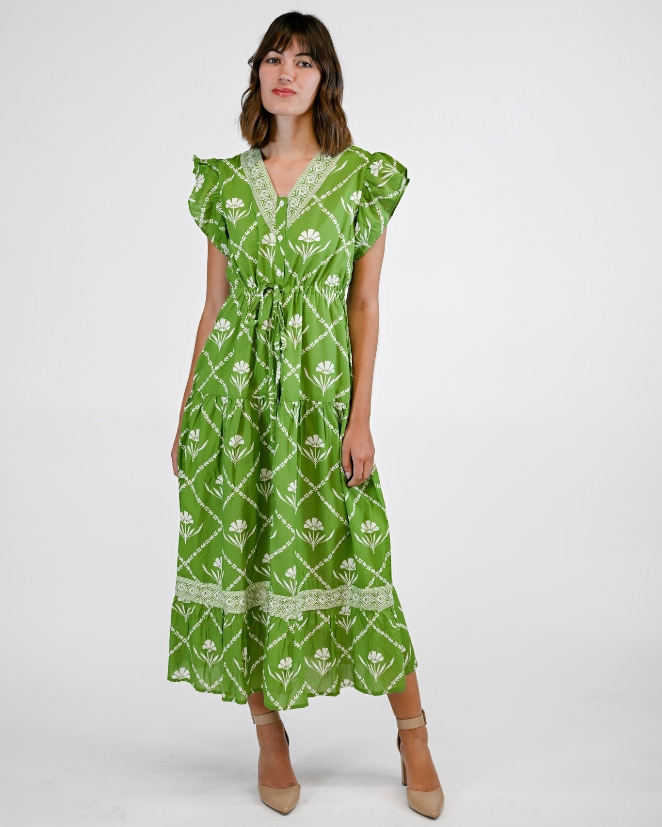 Woman wearing a green patterned dress on a white background