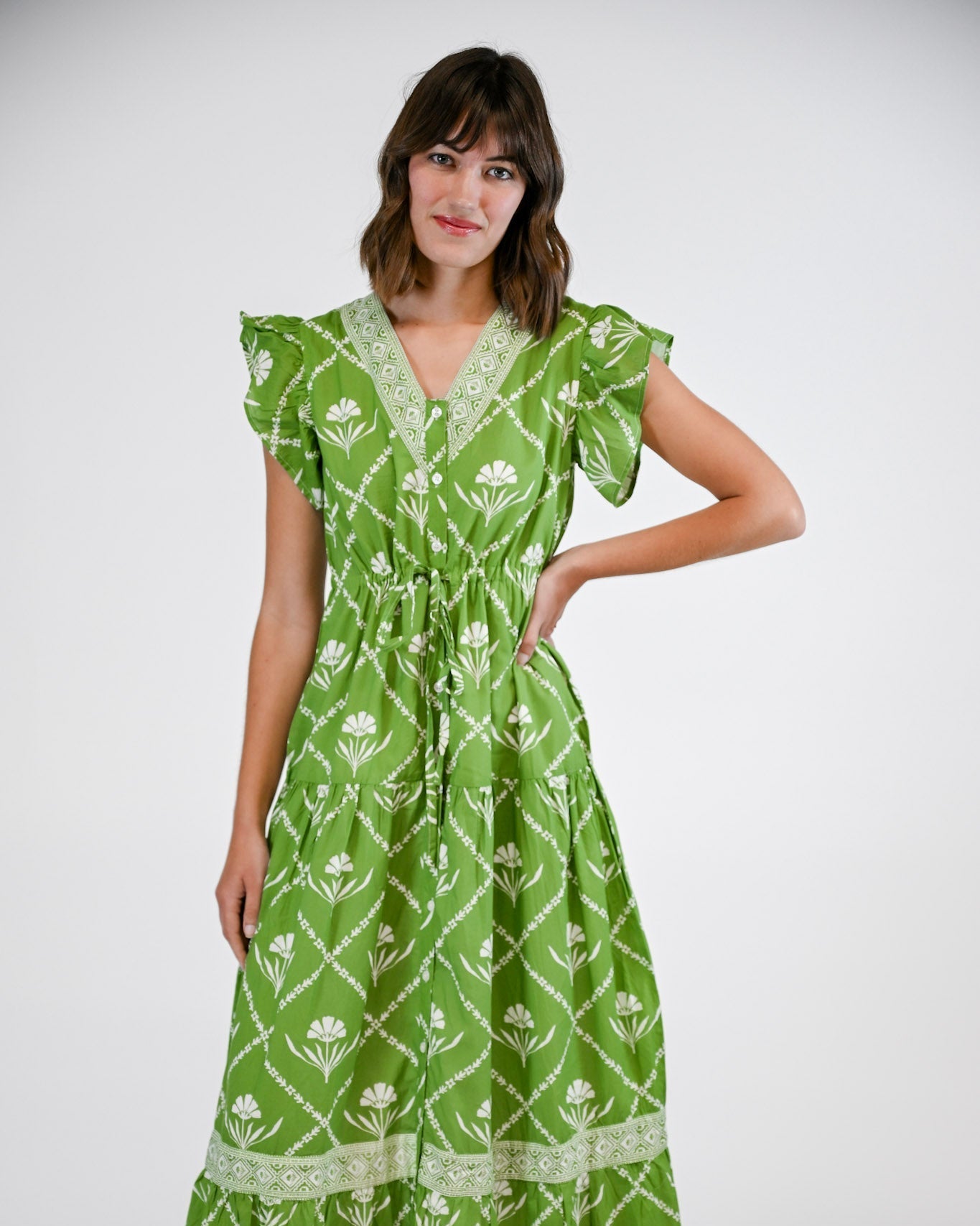 Woman wearing a green dress with white floral pattern on a white background