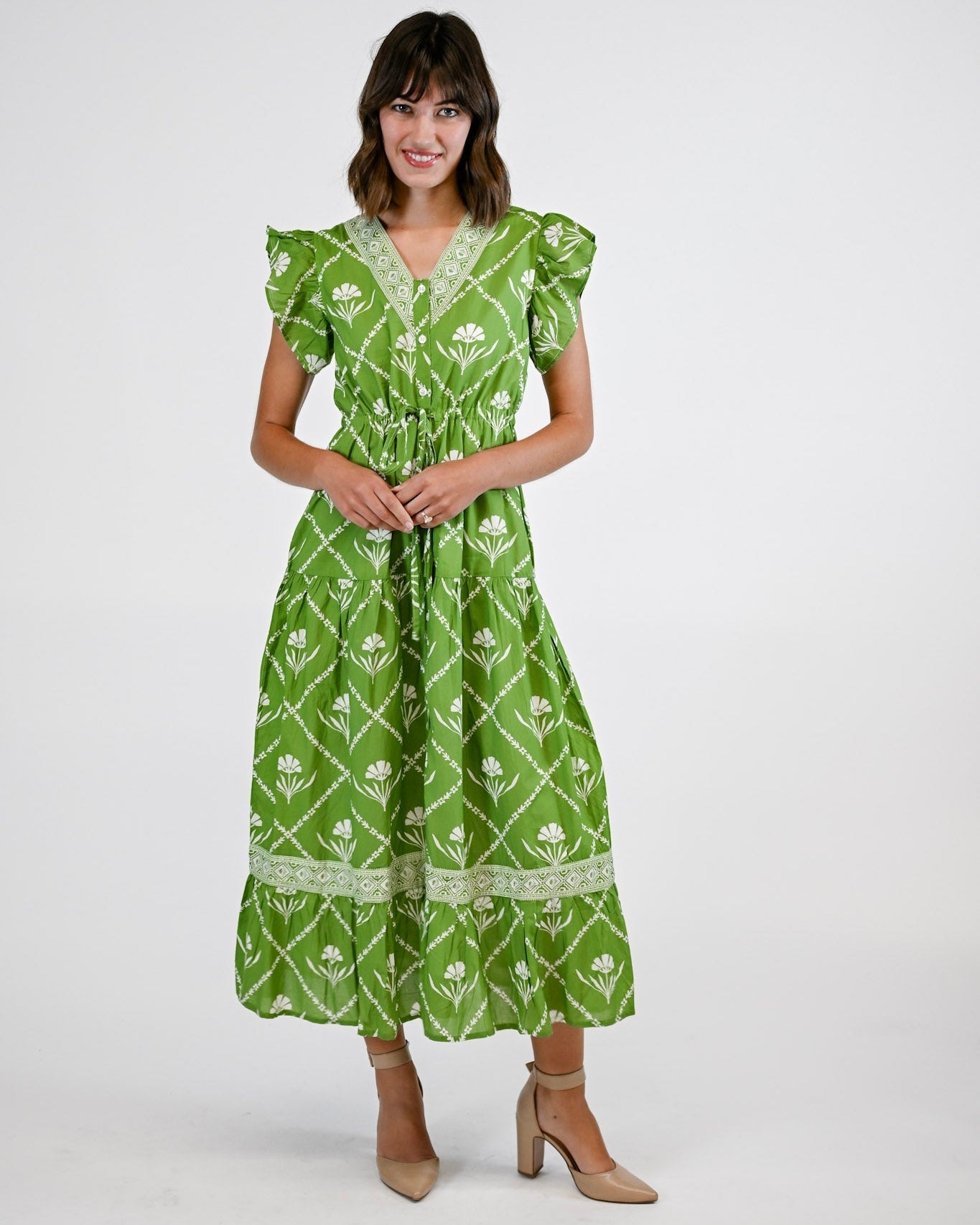 Woman wearing a green patterned dress on a white background