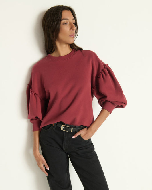 Model wearing a sweatshirt in Russet with black jeans standing in front of a white wall