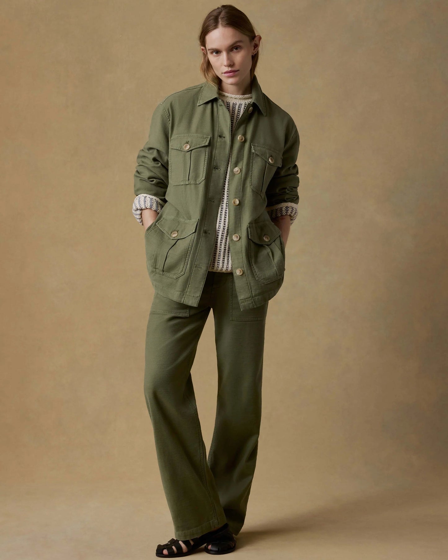 Person wearing a green jacket and pants on a beige background