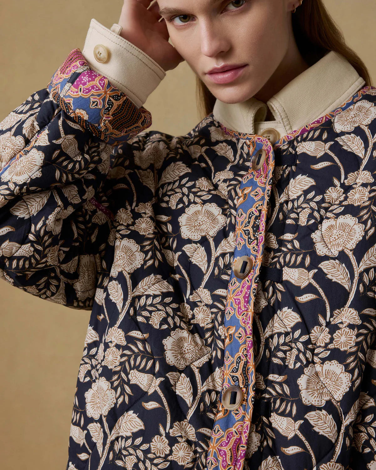 Woman wearing a floral patterned coat with a beige background
