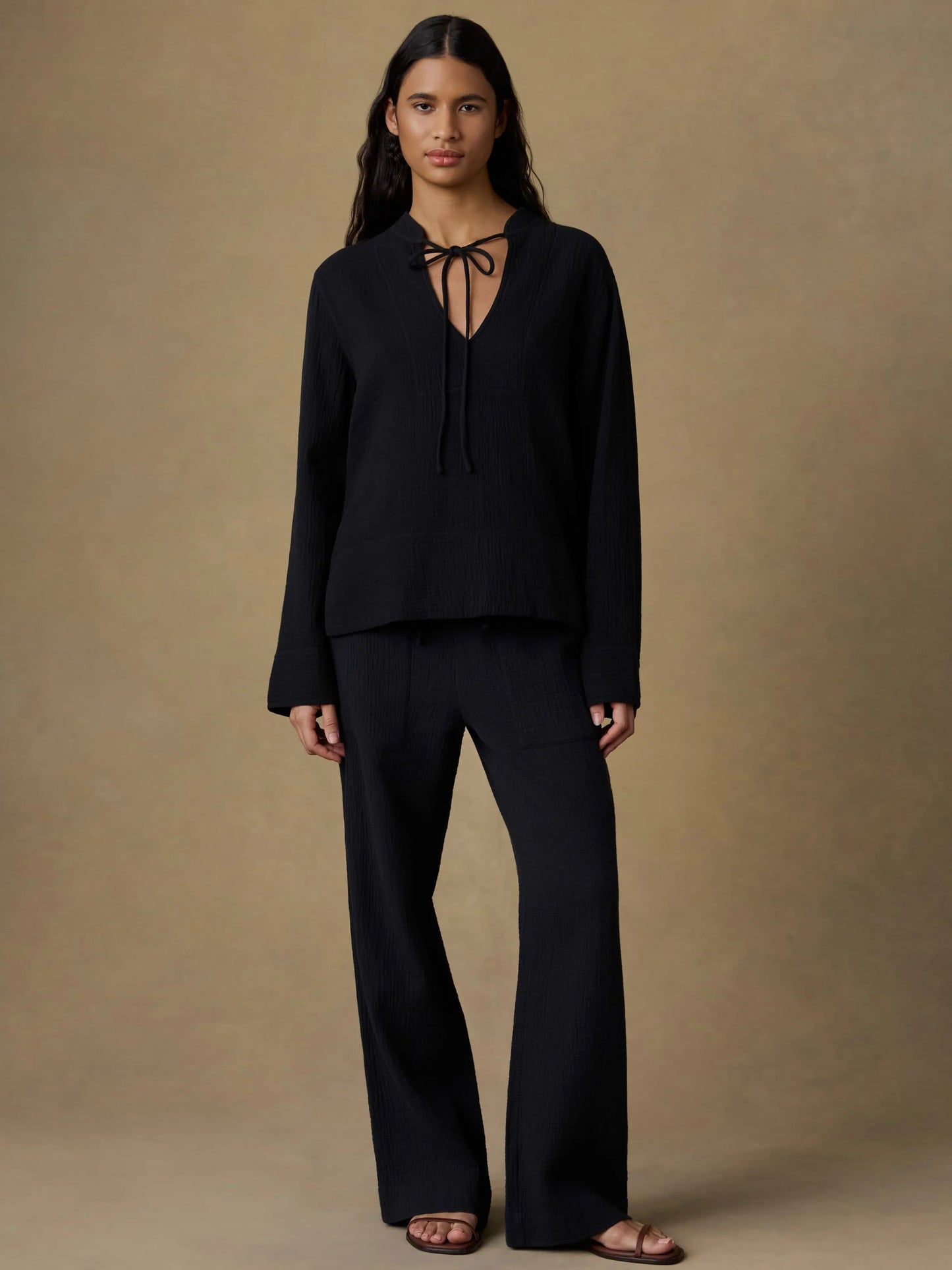Woman wearing a black outfit against a beige background