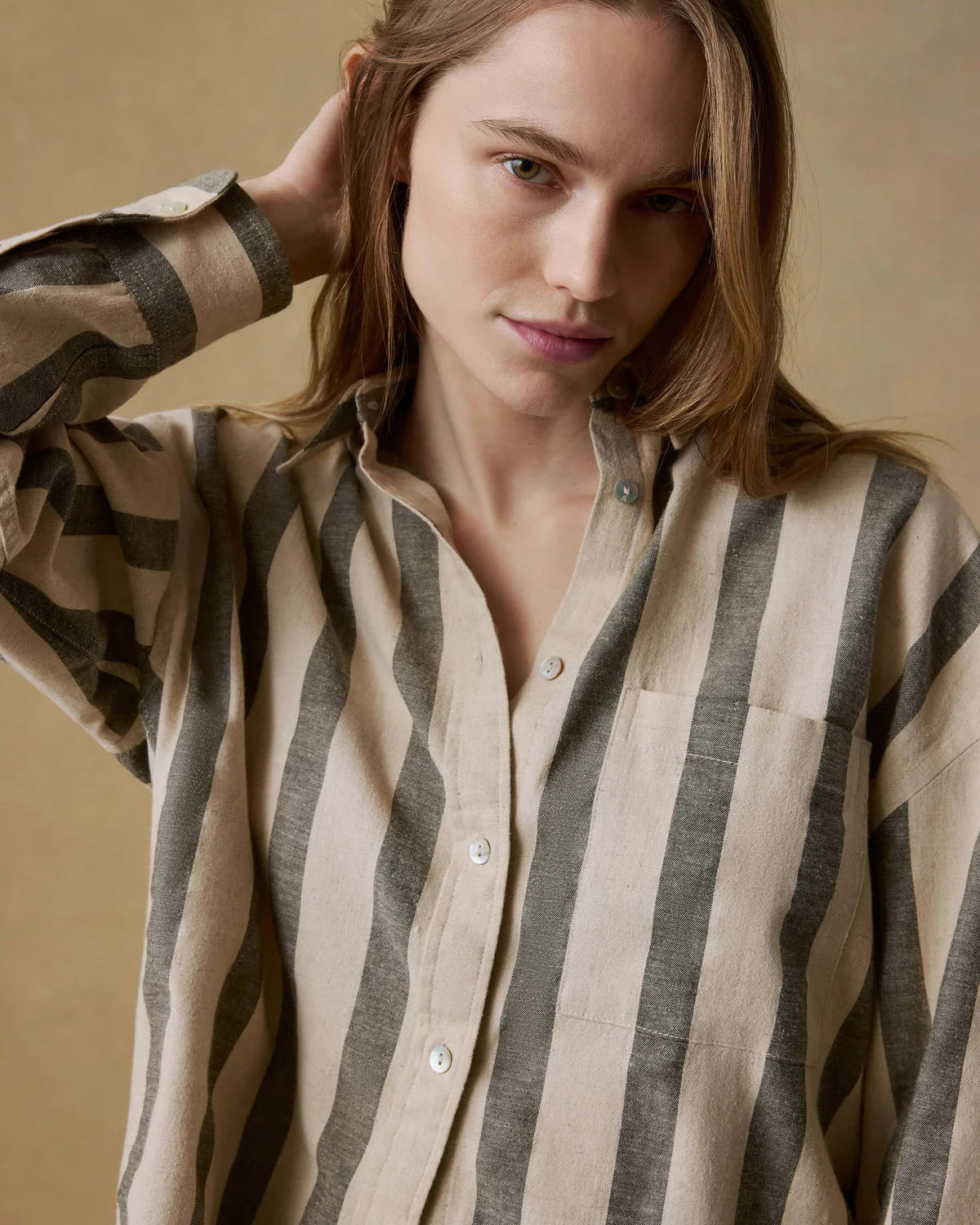 Woman wearing a striped shirt against a beige background