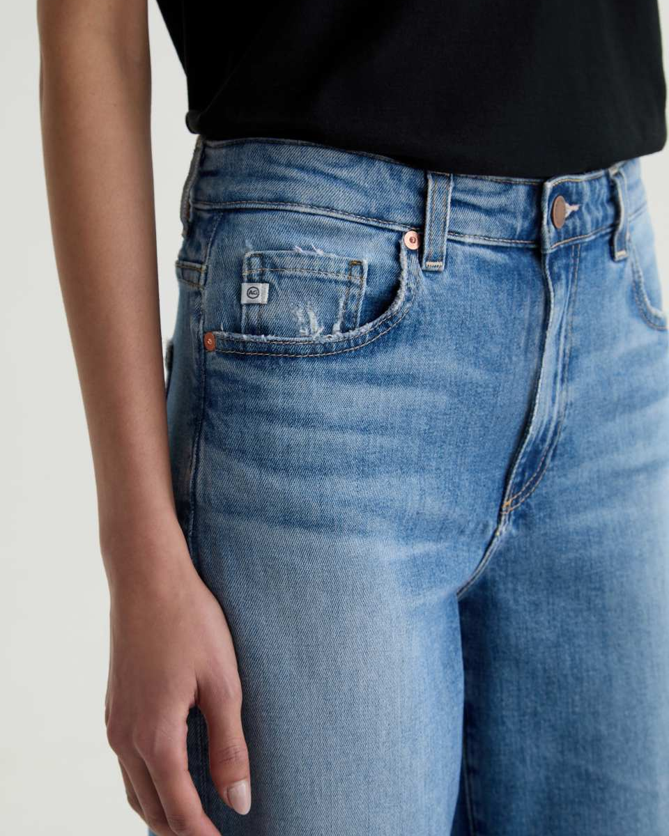 Person wearing blue jeans with a plain background