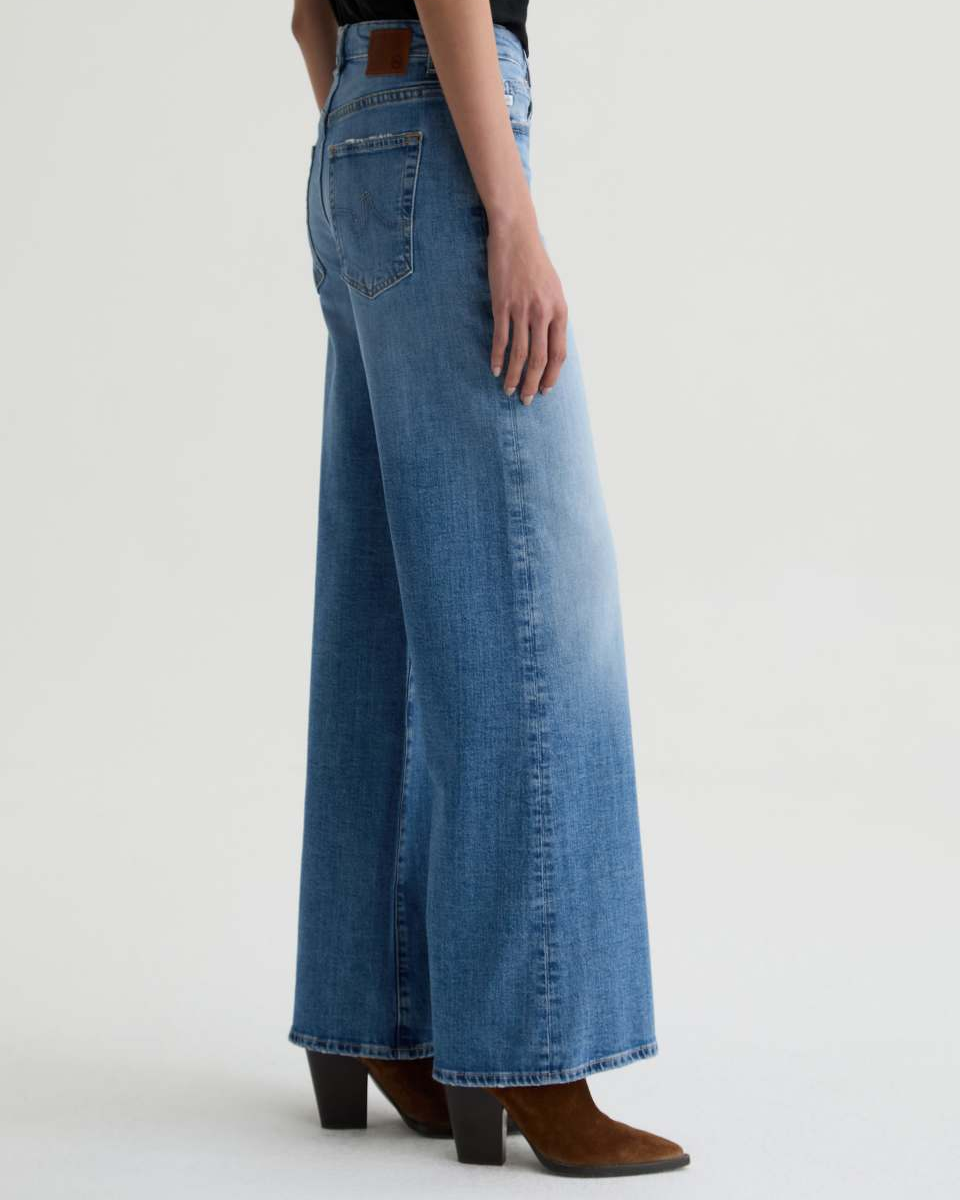Person wearing blue wide-leg jeans on a white background