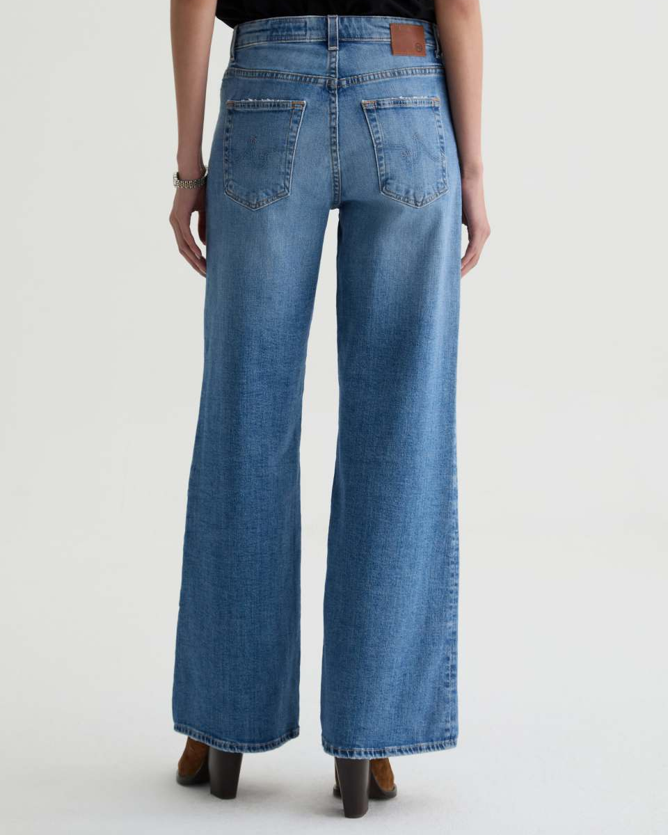 Person wearing blue jeans on a plain background