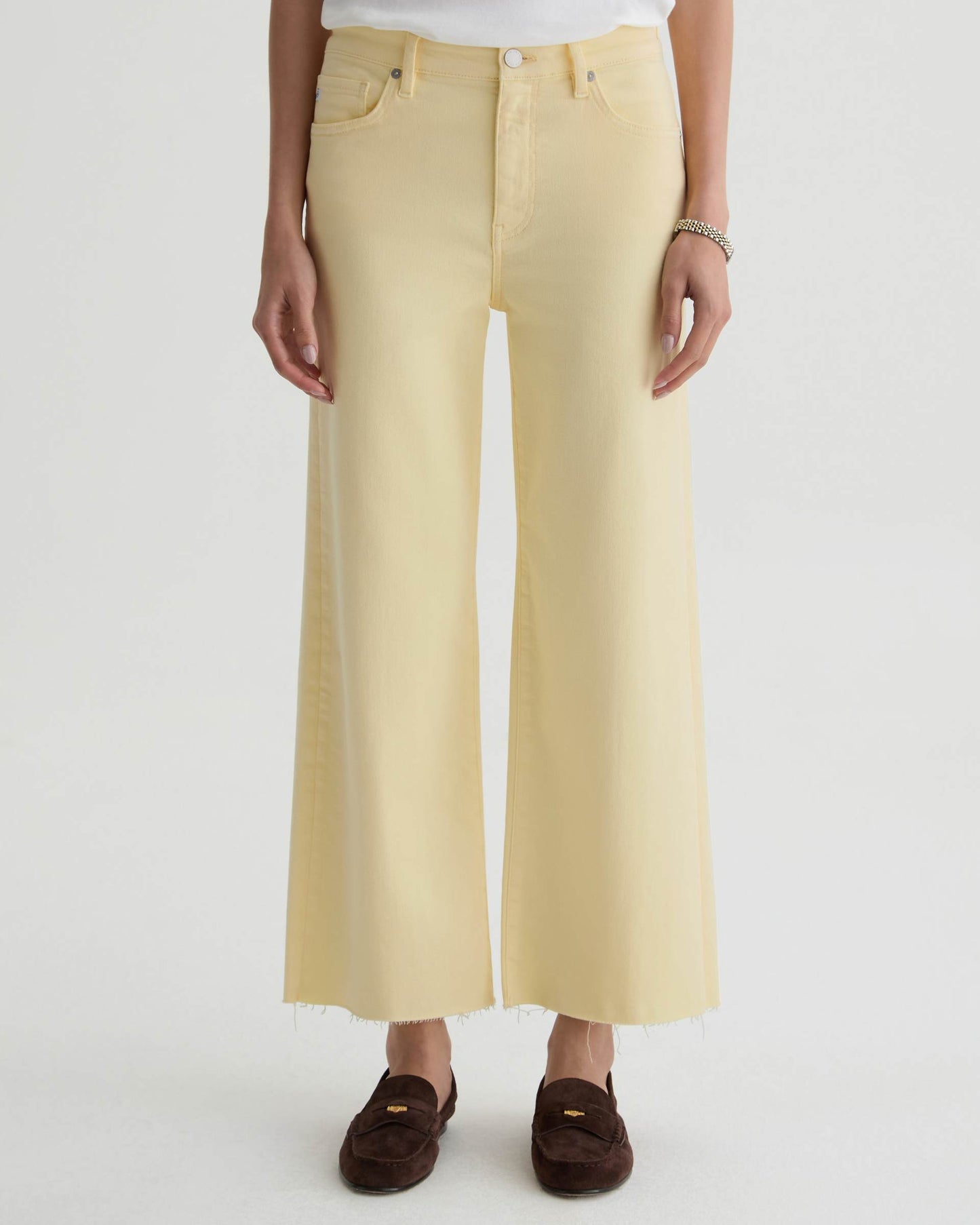 Person wearing light yellow wide-leg pants on a white background