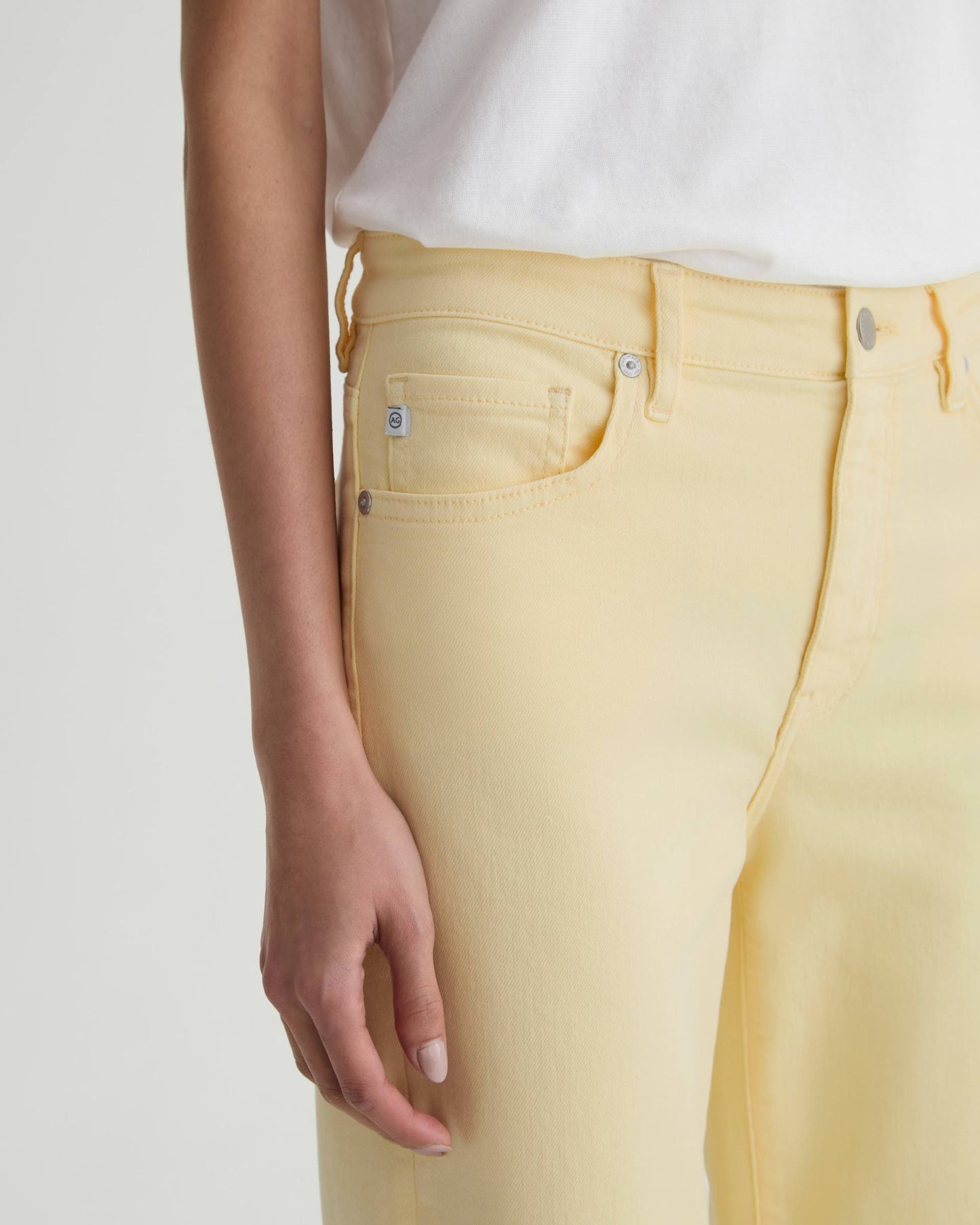 Person wearing light yellow jeans with a white background