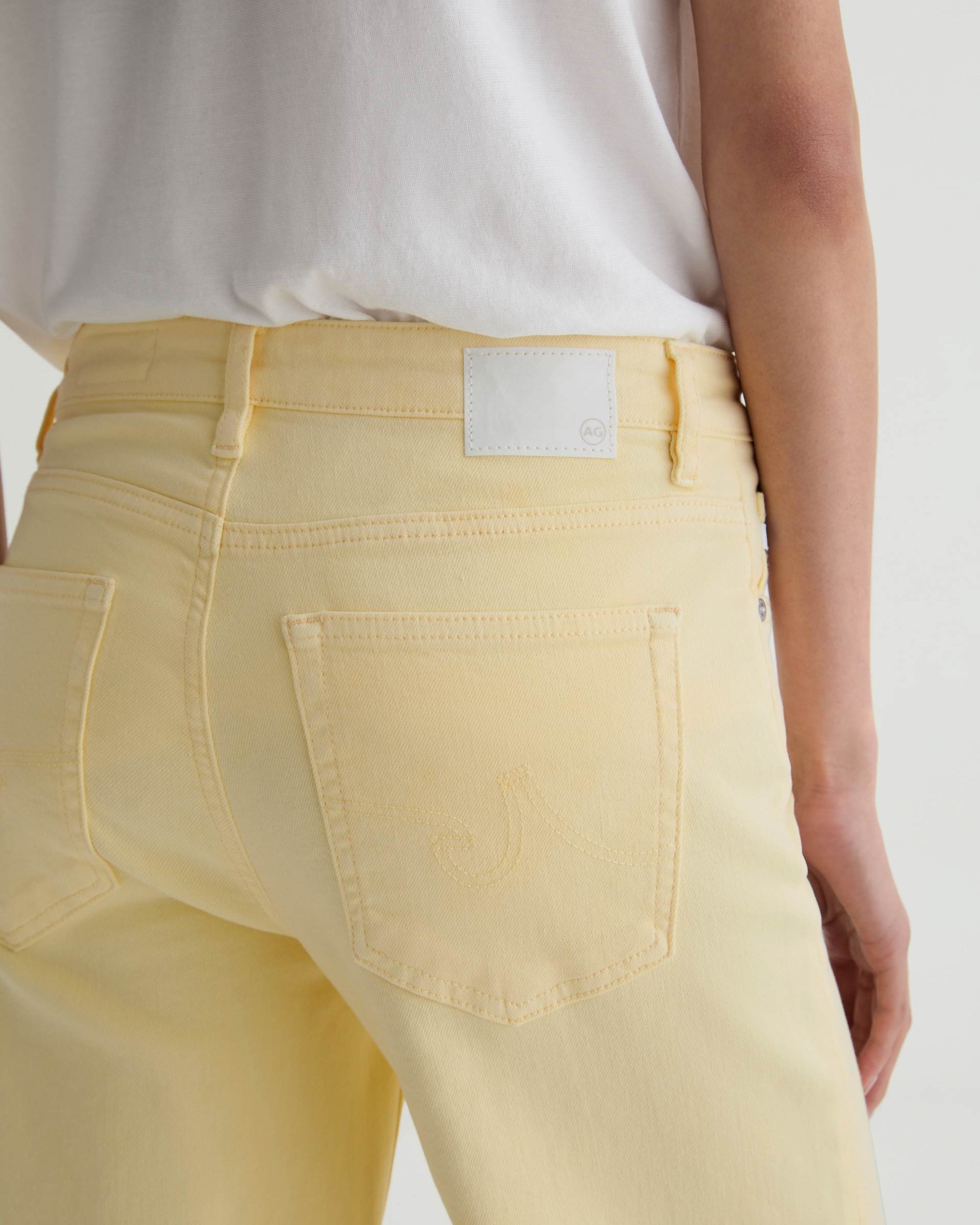 Light yellow jeans with a visible brand label on a plain background