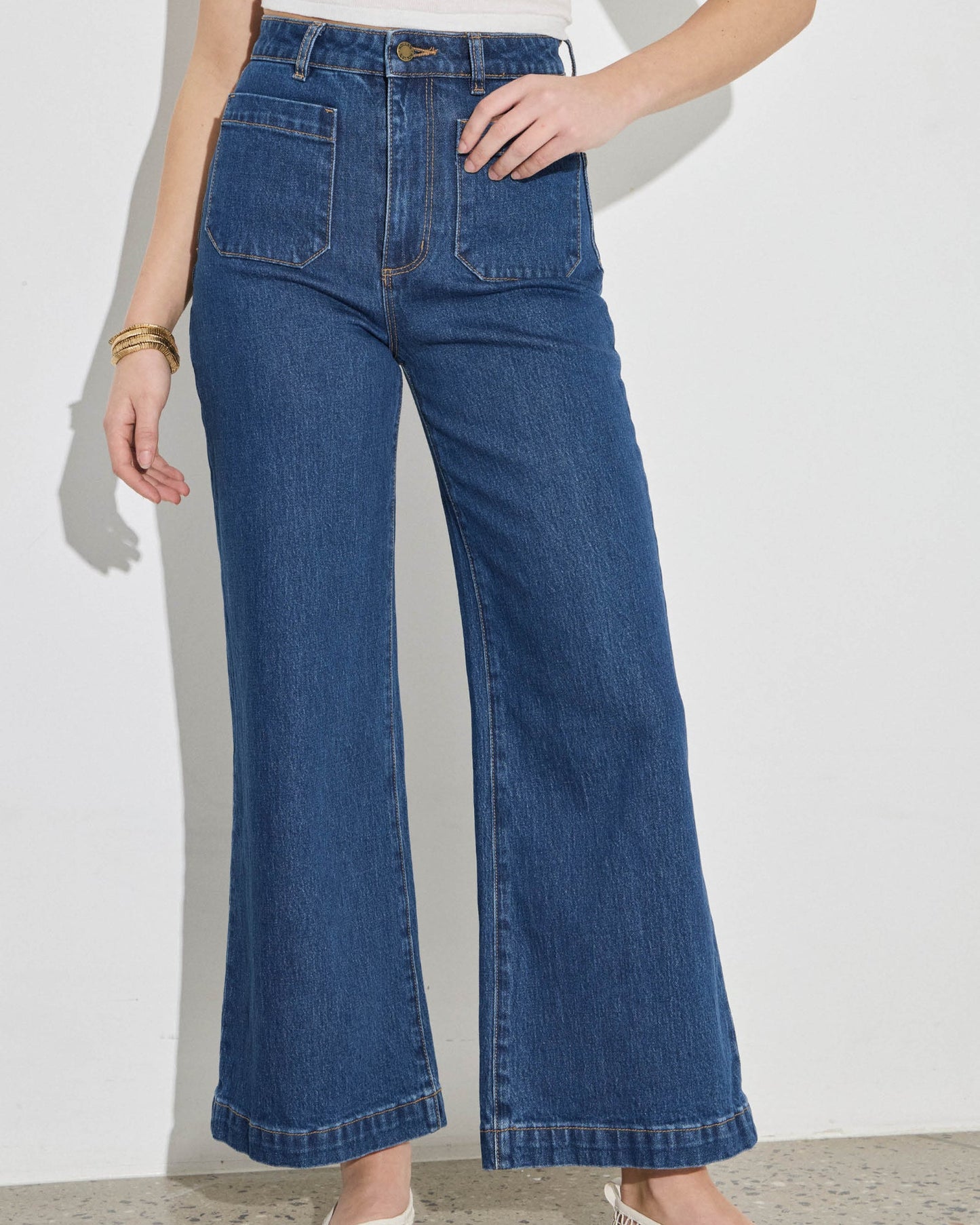 Person wearing blue wide-leg jeans on a plain background