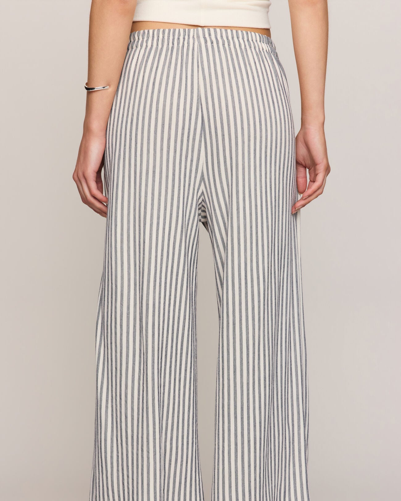 Person wearing black and white striped wide-leg pants on a plain background